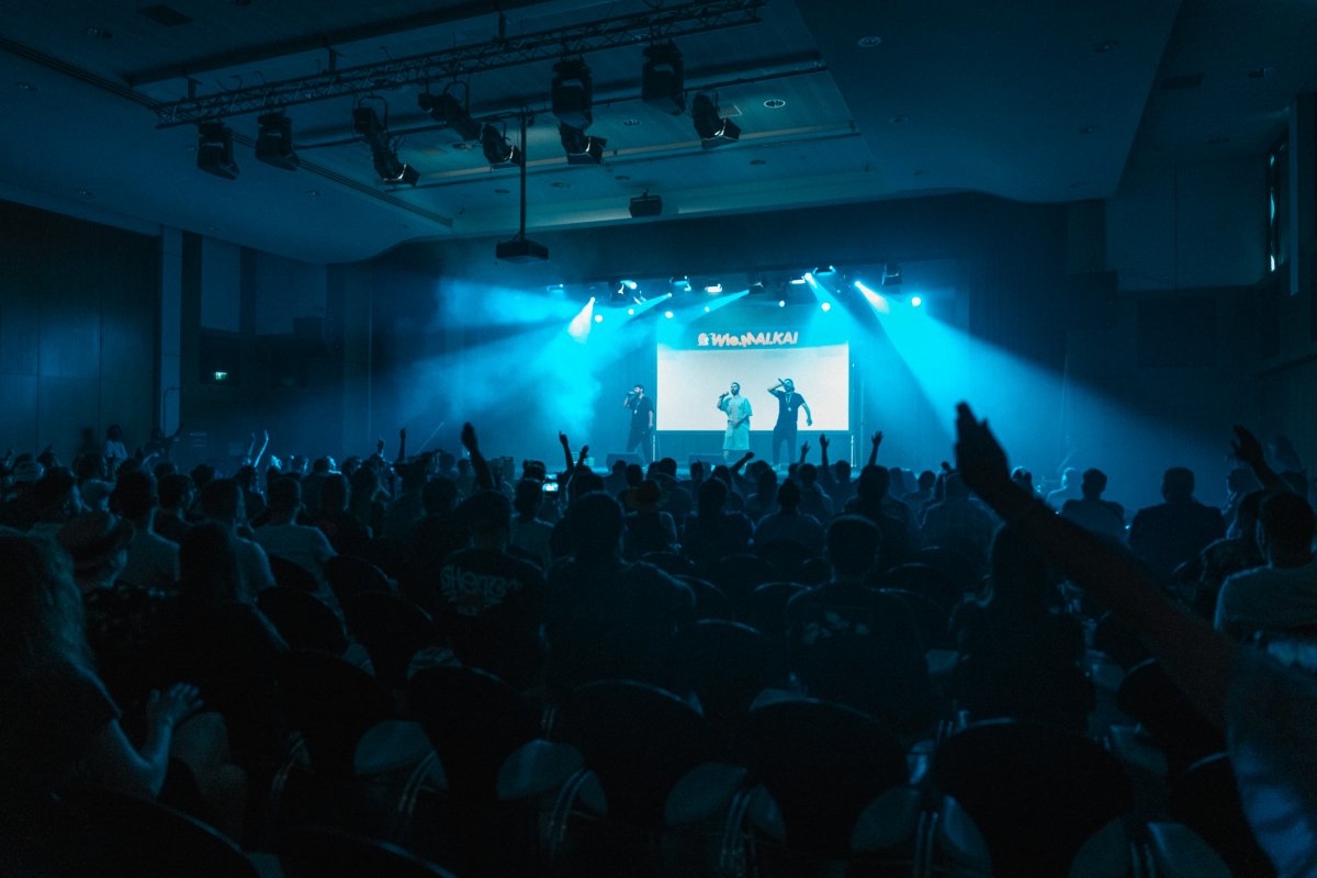 Packed hall during a stage show in blue spotlights